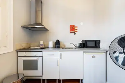 a small kitchen with white cabinets and a sink at GuestReady - Cosme Heritage Apartments in Porto