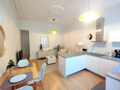 a kitchen with white cabinets and a table and chairs at Elegant duplex, WiFi, Porto center in Porto