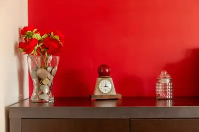 a table with a vase of flowers and a clock at Francos Relaxing Apartment by the metro in Porto