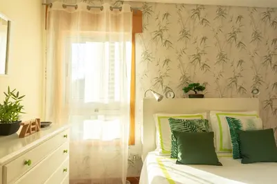 a bedroom with a bed with green pillows and a window at Francos Relaxing Apartment by the metro in Porto