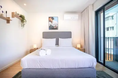 a bedroom with a white bed and a large window at Aires Ornelas Gem, City Escape with Private Parking in Porto