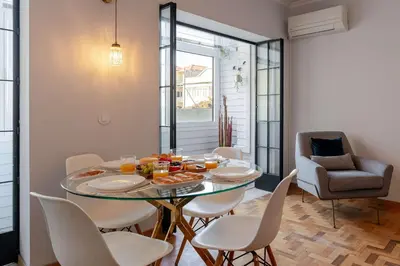 a dining room with a glass table and white chairs at Light-Filled Cedofeita Apt by HostWise in Porto