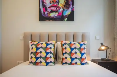 a bed with two pillows and a painting on the wall at Luxury Style 10 with AC Downtown Porto near Metro in Porto