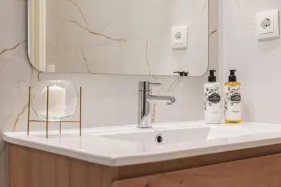 a bathroom sink with a mirror and two bottles on it at Luxury Style 10 with AC Downtown Porto near Metro in Porto