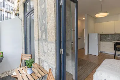 a apartment with a balcony with a table and a refrigerator at Studio Apartment Torrinha in Porto