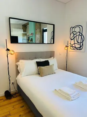 a bedroom with a white bed with a mirror above it at Studio Apartment Torrinha in Porto