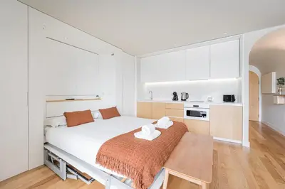 a white bedroom with a large bed and a kitchen at GuestReady - A lovely retreat in Porto in Porto