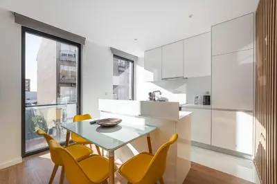 a kitchen with yellow chairs and a table and a kitchen with white cabinets at GuestReady - One perfect home near Marquês in Porto