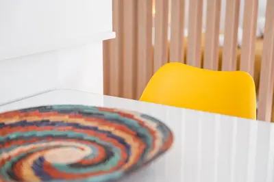 a colorful spiral rug on a white table with a yellow chair at GuestReady - One perfect home near Marquês in Porto