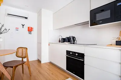 a kitchen with white cabinets and a black oven at Povoa Terrace, A Curated Escape with Large Balcony in Porto