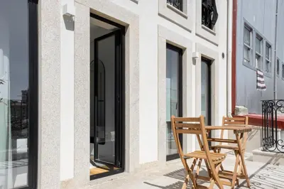 a wooden chair sitting next to a table on a balcony at Povoa Terrace, A Curated Escape with Large Balcony in Porto