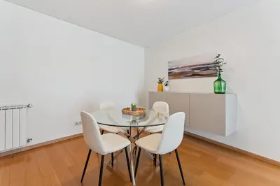 a dining room with a glass table and white chairs at GuestReady - Modern apartment in Boavista in Porto