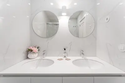 a white bathroom with two sinks and two mirrors at GuestReady - Lovely family home in Boavista in Porto