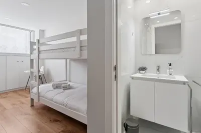 a white bedroom with a bunk bed and a sink at GuestReady - Lovely family home in Boavista in Porto