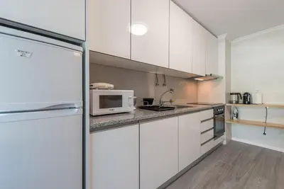 a kitchen with white cabinets and a microwave at GuestReady - Sunny patio paradise in Porto in Porto