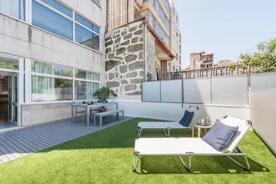 an apartment patio with grass and chairs and a table at GuestReady - Sunny patio paradise in Porto in Porto