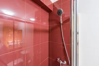 a shower with a red tiled wall at GuestReady - Sunny patio paradise in Porto in Porto
