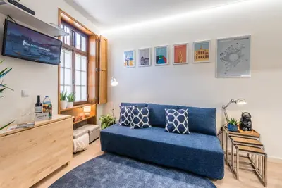 a living room with a blue couch and a tv at GuestReady - Timber-framed luxe stay in Porto