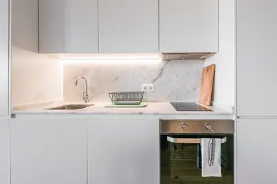 a kitchen with white cabinets and a sink at GuestReady - One Step Closer in Porto
