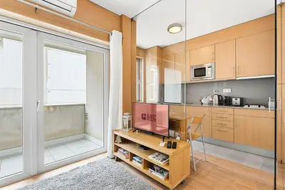 a kitchen with wooden cabinets and a large window at GuestReady - Cosy Studio Near Arrábida Shopping in Vila Nova de Gaia