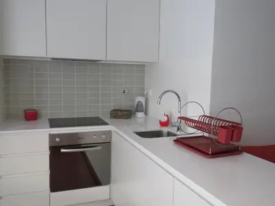 a kitchen with white cabinets and a sink and a red appliance at Miguel Bombarda - Porto Houses & Suites in Porto