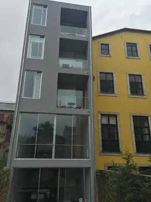 a tall building with windows in front of a yellow building at Miguel Bombarda - Porto Houses & Suites in Porto