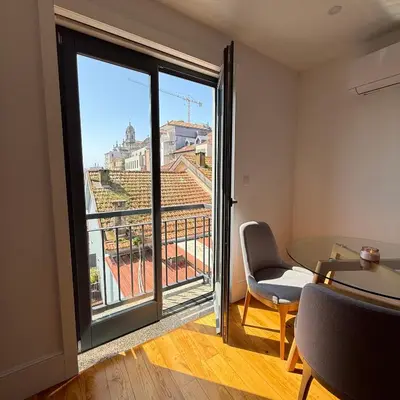 a kitchen with white cabinets and a wooden floor at Flores Street Apartment - Porto City Center in Porto