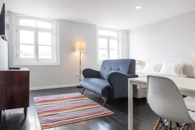 a living room with a bed and a blue chair at Porto República Suites in Porto