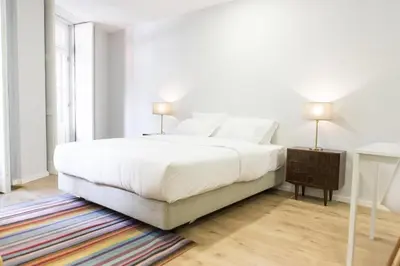 a white bedroom with a large bed and a table at Porto República Suites in Porto