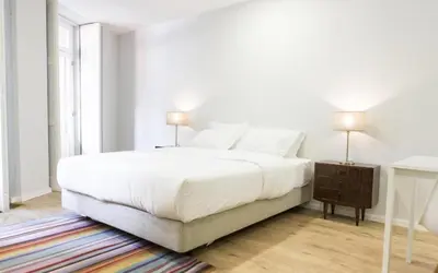 a white bedroom with a large bed and a window at Porto República Suites in Porto
