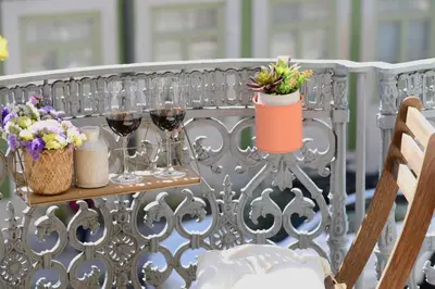 a table with glasses of wine and flowers on a fence at Studio Palazzo, Antique Charm with Romantic Balcony and AC in Porto