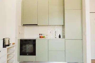 a white kitchen with white cabinets and a stove at Apartment 1 min walk from Metro and Trendiest Neighborhood Bonfim in Porto