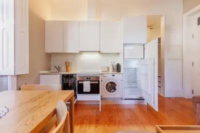 a kitchen with white cabinets and a wooden table at Cozee Camões in Porto