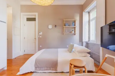 a bedroom with a large bed and a tv at Cozee Camões in Porto