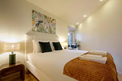 a bedroom with a large white bed and a painting on the wall at Magnolia 3 Luxury with AC Metro Downtown Porto in Porto