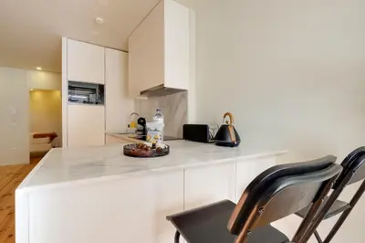 a kitchen with white cabinets and a counter with chairs at Magnolia 3 Luxury with AC Metro Downtown Porto in Porto