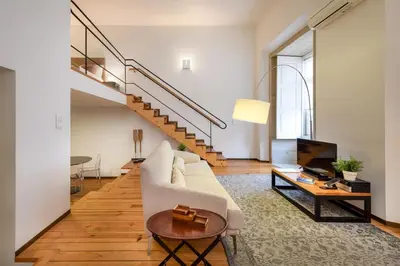 a living room with a white couch and a staircase at Condes de Azevedo Palace Apartments in Porto