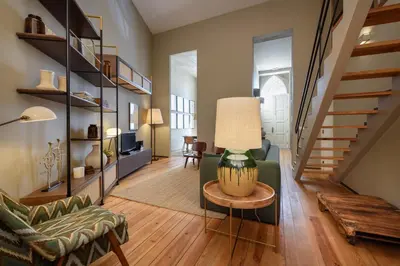a living room with a staircase and a table with a lamp at Condes de Azevedo Palace Apartments in Porto
