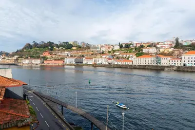 a river with a boat in the middle of a city at Riverfront Heritage House in Vila Nova de Gaia
