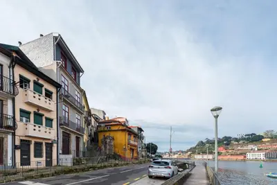 a street with buildings and a car parked next to a river at Riverfront Heritage House in Vila Nova de Gaia