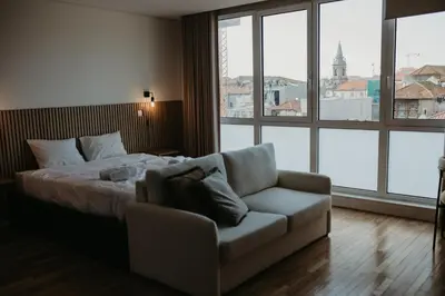 a bedroom with a bed and a couch and windows at Bolhão Downtown in Porto
