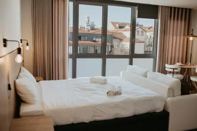 a white bed in a room with a large window at Bolhão Downtown in Porto