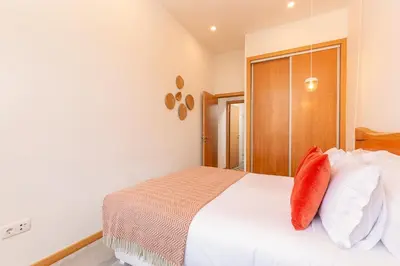 a bedroom with a bed with white sheets and red pillows at YOUROPO - Cosy in Porto