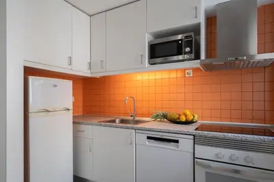 a kitchen with white cabinets and an orange tile wall at Authentic Porto Home by HostWise in Porto