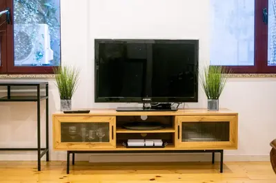 a wooden entertainment center with a flat screen tv on it at Magnificent Cais de Gaia Duplex in Vila Nova de Gaia
