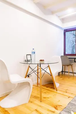a dining room with white chairs and a glass table at Magnificent Cais de Gaia Duplex in Vila Nova de Gaia