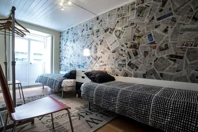 a bedroom with two beds and a wall covered in newspapers at Welcome to my city 2 in Porto