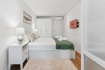 a white bedroom with a bed and a nightstand at GuestReady - Elegant stay in Central Porto in Porto