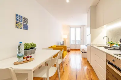 a kitchen and living room with a white table and chairs at Oporto Center Studio in Porto