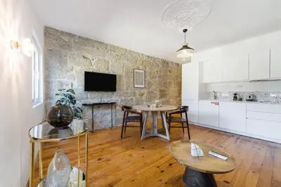 a living room with a table and a stone wall at Vila Rio Guest House in Vila Nova de Gaia